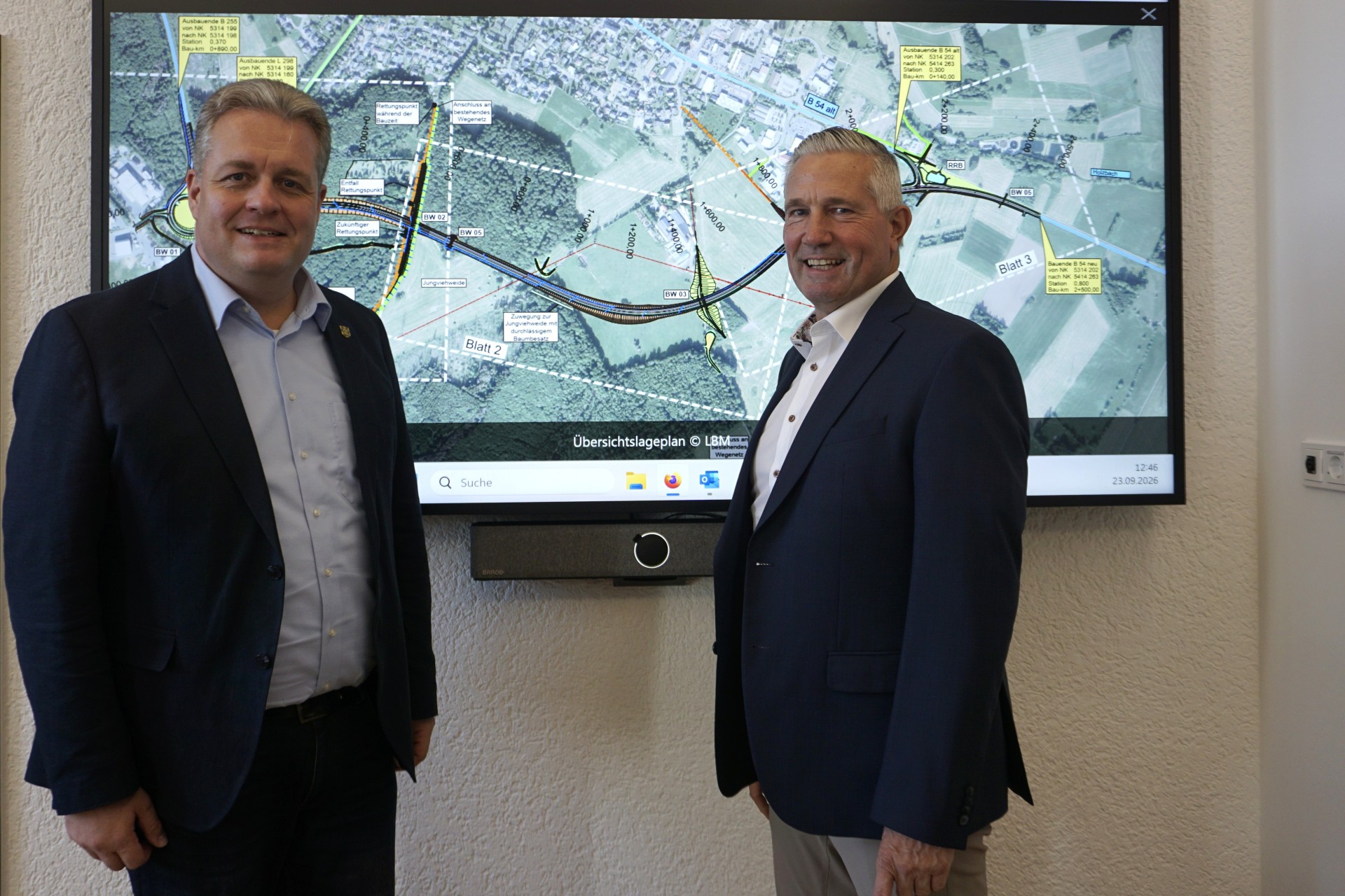 Landrat Klaus Lütkefedder und Bürgermeister Gerrit Müller vor einer Planungsansicht für die Ortsumgehung Rennerod