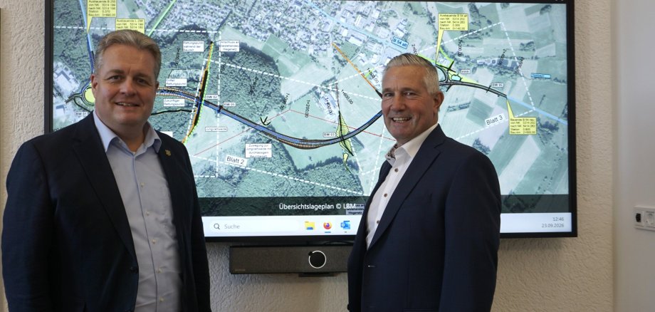 Landrat Klaus Lütkefedder und Bürgermeister Gerrit Müller vor einer Planungsansicht für die Ortsumgehung Rennerod
