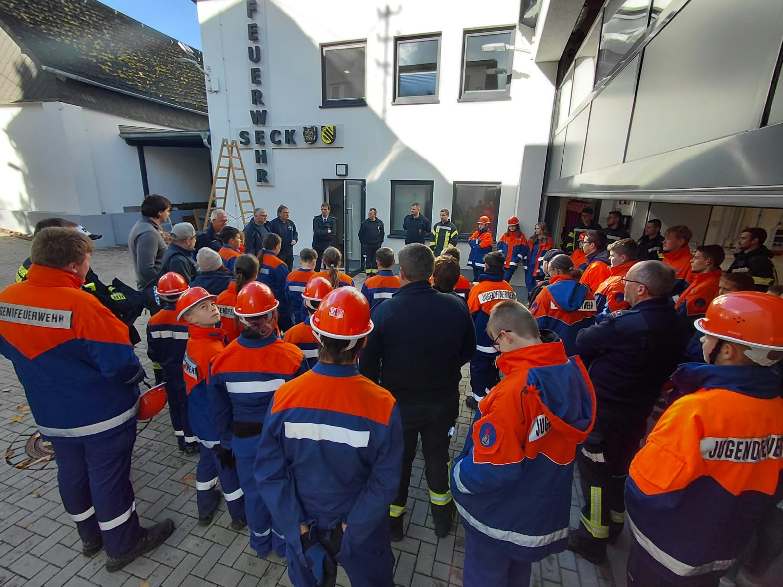 Kinder und Jugendliche in Feuerwehrkleidung stehen am Feuerwehrgebäude in Seck