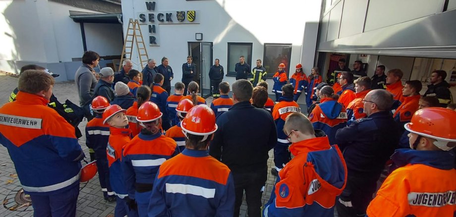 Kinder und Jugendliche in Feuerwehrkleidung stehen am Feuerwehrgebäude in Seck