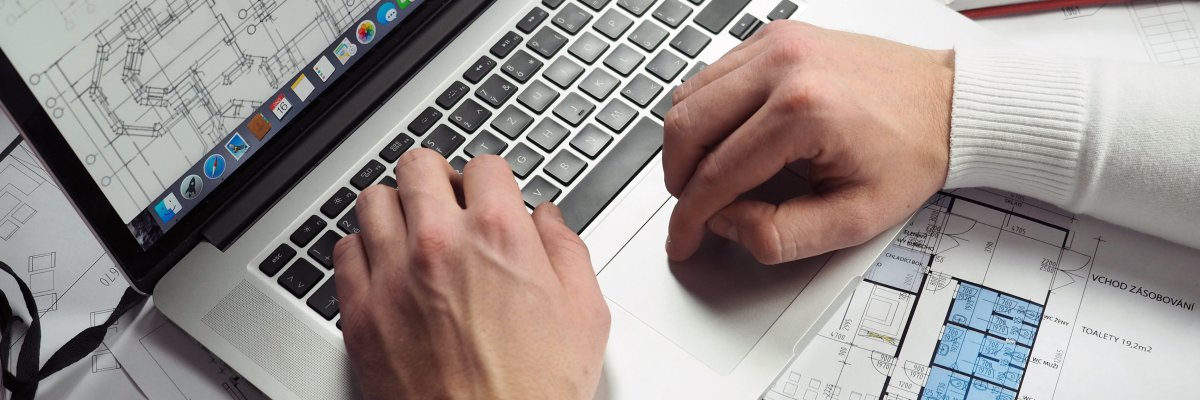 Ein Mann arbeitet an einem Laptop, auf dem eine technische Zeichnung zu sehen