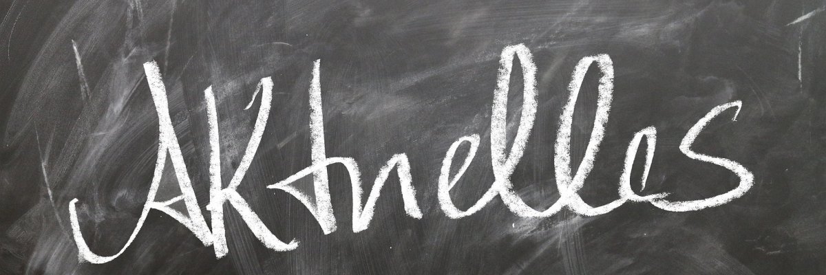 Auf einer schwarzen Wandtafel ist mit Kreide das Wort Aktuelles geschrieben